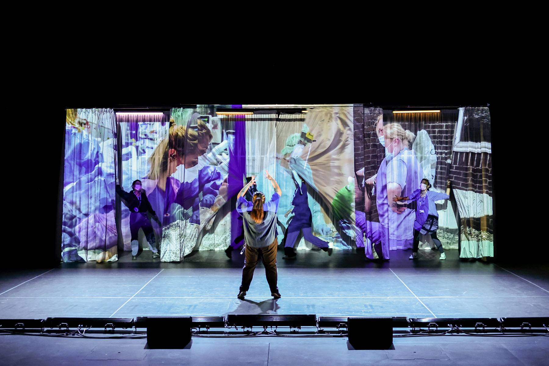 performer on stage with vibrant background projections